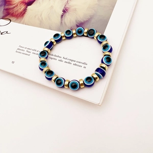 Close-up of blue evil eye beads with golden metal spacers on a stretch bracelet