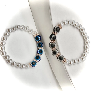 Detail of baroque pearl bracelets with evil eye charms and rose gold crystal spacers