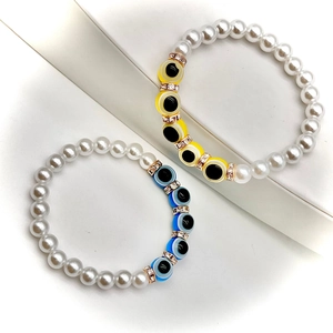 Macro shot of Baroque pearl bracelet with yellow and blue evil eye charms and crystals
