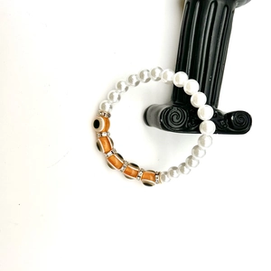 Detail of baroque pearl bracelet with orange evil eye beads on a Greek pedestal