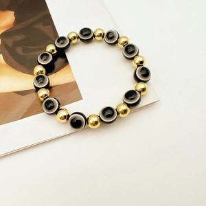 Dettaglio macro del bracciale etnico con perle in agata nera e sfere in metallo oro