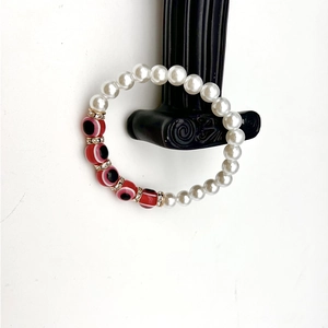 Close-up of handmade evil eye bracelet with white pearls and sparkling crystal spacers