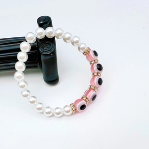 Macro detail of Evil Eye bracelet with pink beads, baroque pearls and gold crystal spacers
