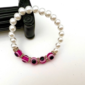 Detailed close-up of baroque pearl bracelet with pink evil eye beads and gold spacers