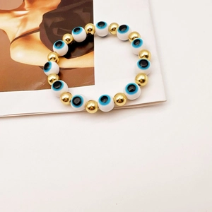 Dettaglio del bracciale elastico con perline dorate e sfere con occhio greco blu