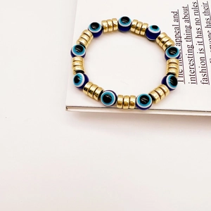Detailansicht eines elastischen Evil-Eye-Perlenarmbands mit blauen Perlen und Gold