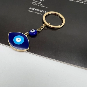 Macro detail of Turkish evil eye keychain with blue enamel charms and gold plating
