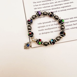 Detail of beaded bracelet with black striped beads, Hamsa Hand and evil eye charm