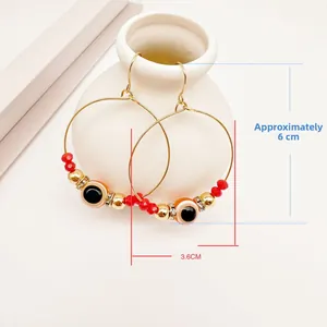 Detail showing evil eye hoop earrings with red beads hanging on a white vase, size approx 6cm