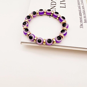 Detail of purple Evil Eye beads and gold spacers on a stylish stretch bracelet