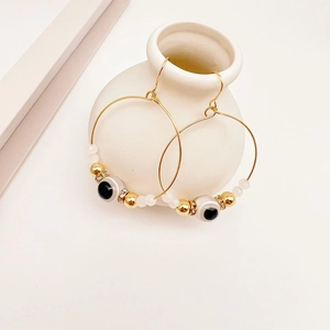 Detail of gold evil eye hoop earrings with blue glass beads and sparkling rhinestones