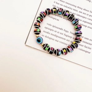 Macro detail of elastic evil eye bead bracelet with colorful patterns on black stones
