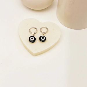 Nahaufnahme der Evil Eye Creolen mit Emaille-Anhängern auf weißem Herz-Stein-Display
