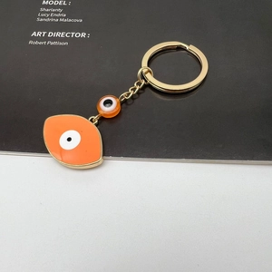Detail of orange Evil Eye keychain with zinc alloy frame and golden metal link chain