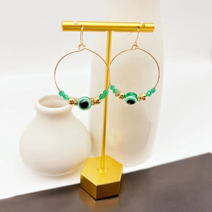 Golden hoop earrings with green Evil Eye bead and sparkling rhinestone accents