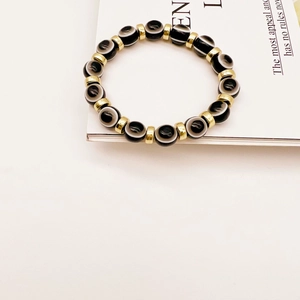 Detailed close-up of Evil Eye beads and gold cylinders on a stretch bracelet