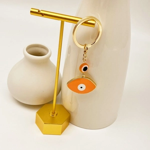 Detail of Turkish evil eye keychain with orange pendants on gold display stand
