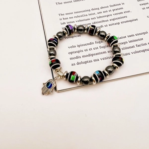 Macro shot of colorful striped beads and Hamsa Hand evil eye charm on elastic bracelet