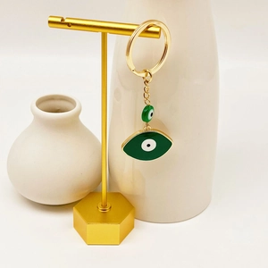 Macro detail of a gold-plated evil eye keychain with green enamel on a golden stand