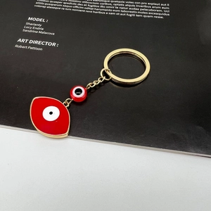 Detailed macro view of red enamel evil eye charms on a golden metal keychain link