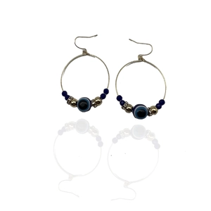 Golden hoop earrings with blue evil eye beads and sparkling crystals on white background