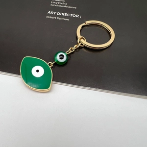 Detail view of a green Evil Eye pendant keychain with gold plating and beaded accents
