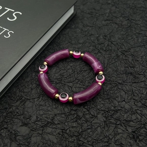 Detail of bohemian purple tube beads and pink evil eye charms with golden spacers
