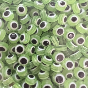 Detailed macro view of light green translucent Evil Eye flat beads for DIY jewelry making