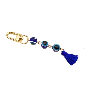 Golden evil eye keychain featuring three blue beads and a dark blue silk tassel pendant