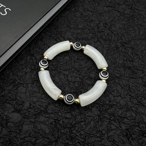 Golden Evil Eye beaded bracelet with acrylic white tubes on black background