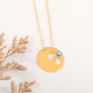 Detalle del collar de ojo turco dorado con colgante de huellas de manos y pies
