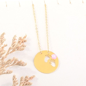 Detalle de collar dorado ojo turco con colgantes calados de manos y pies de bebé