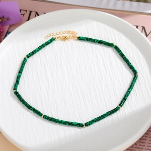 Dettaglio di perle in malachite verde cilindriche con sfere dorate e chiusura regolabile