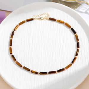 Dettaglio della collana con pietre occhio di tigre, perline dorate e chiusura a moschettone