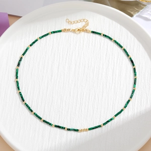 Dettaglio di perle di malachite verde con distanziatori dorati e chiusura a moschettone su piatto