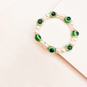 Vista de detalle de perlas blancas y cuentas de ojo turco verde en pulsera bohemia