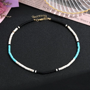 Dettaglio della collana girocollo con pietre colorate e chiusura dorata su sfondo nero
