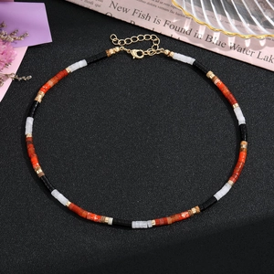 Dettaglio di collana artigianale con perline di pietra, chiusura e catena dorata