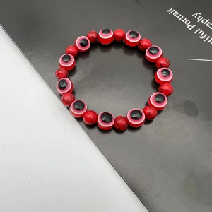 Macro shot of red natural stone beads and evil eye charms on a beaded elastic bracelet