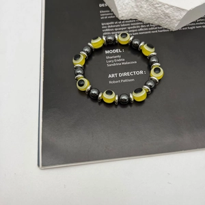 Detailed view of elastic beaded bracelet with yellow evil eye charm and hematite beads