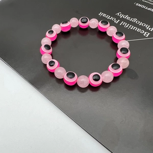 Detail of pink evil eye beads and translucent round stones on a beaded bracelet