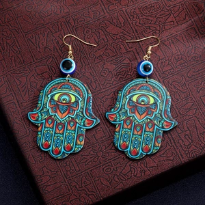 Makroaufnahme von Hamsa-Hand-Ohrringen mit blauen Evil-Eye-Perlen und Mandala-Mustern