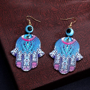 Detail von Hamsa-Hand-Ohrringen mit Mandala-Mustern und blauen Perlen gegen das böse Auge