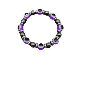 Elastic bracelet with purple Evil Eye beads and dark grey hematite stones on white background