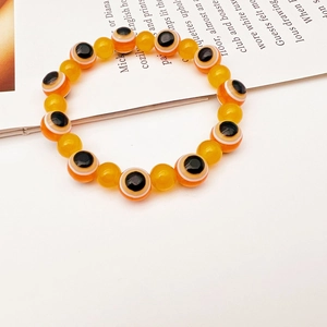 Detail of beaded evil eye bracelet featuring orange motifs and translucent yellow beads