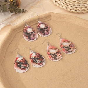 Water-drop leather earrings with gothic skull and rose patterns on a stone tray