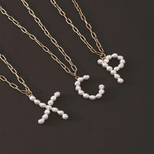 Detail of hip-hop gold chain necklace with white pearl initial pendants X C and P
