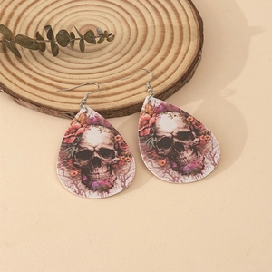 Macro detail of teardrop faux leather earrings featuring skull and floral printed patterns