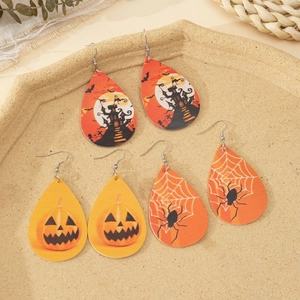 Detailed close-up of Halloween faux leather leaf earrings with pumpkin and castle prints