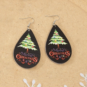 Detailed macro view of wooden teardrop earrings with Merry Christmas tree pattern